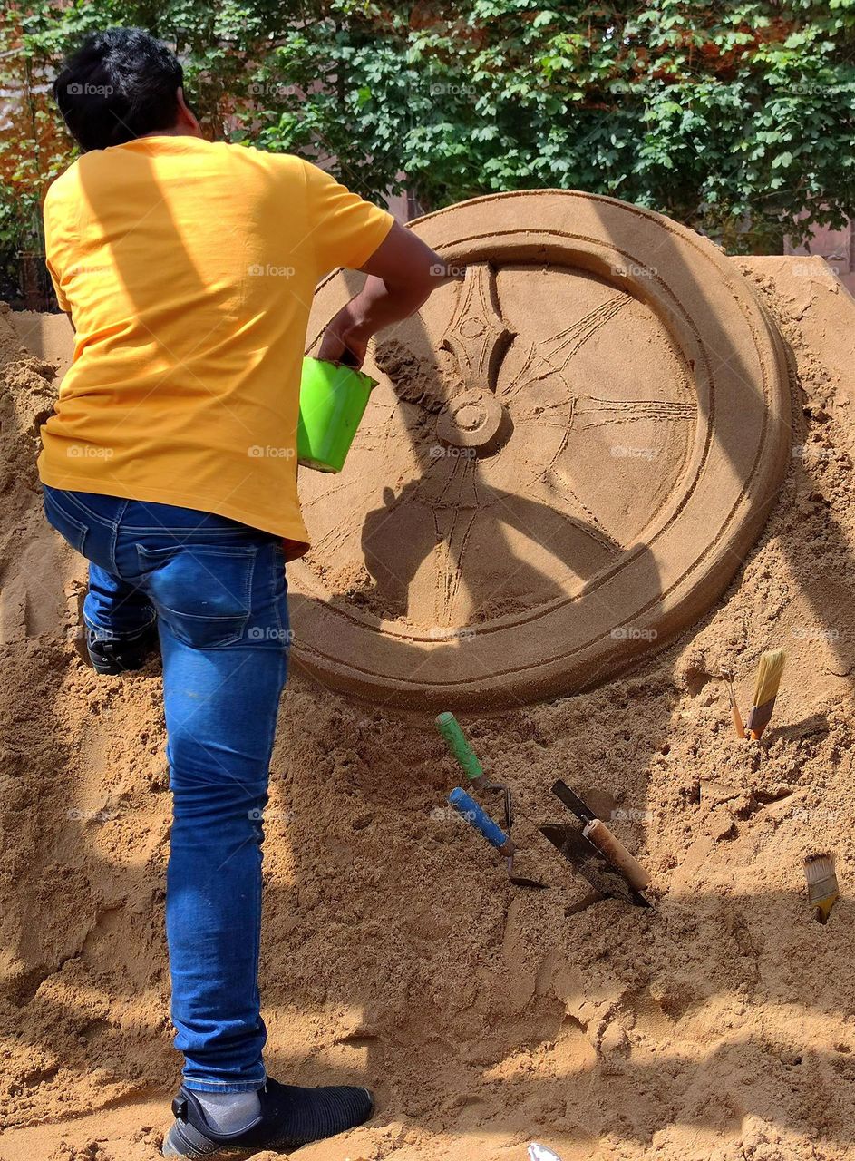 Summer. A man makes a sculpture out of sand.