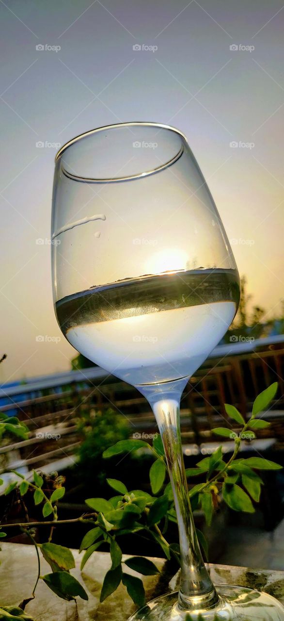 Beautiful view of the sun setting from the balcony of my house Sun set in water filled in a glass tumbler .