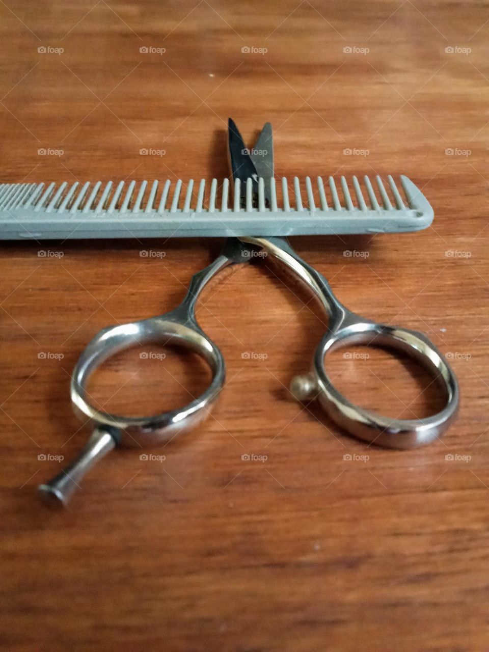 A pair of cutting tools, comb and scissor on the table.
