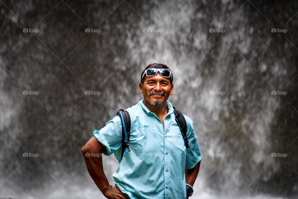 Fit man with a beard staying close to a waterfall