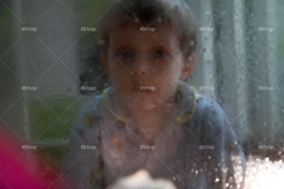 sad boy portrait through wet glass