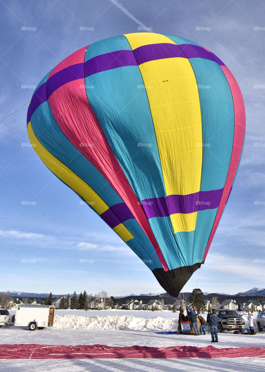 A hot air balloon festival in the winter creates a colorful scene. This balloon is almost inflated.