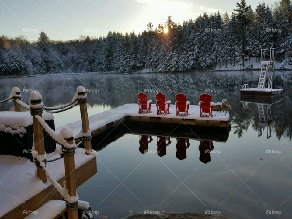 Reflection of forest and pier on lake in winter