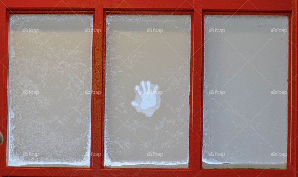 Handprint on a frost covered window.