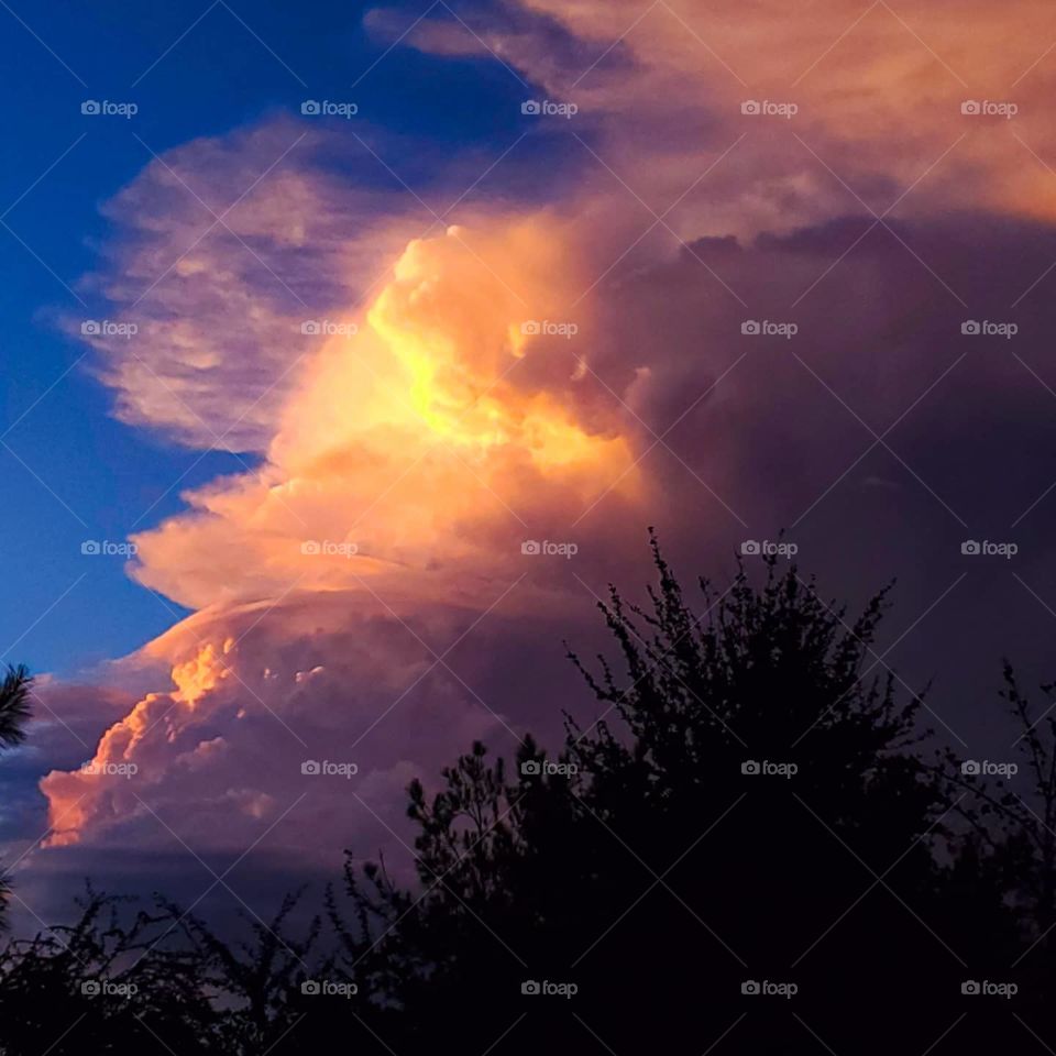 A huge thunder head moves past while the sunset glows through it offering impressive colors
