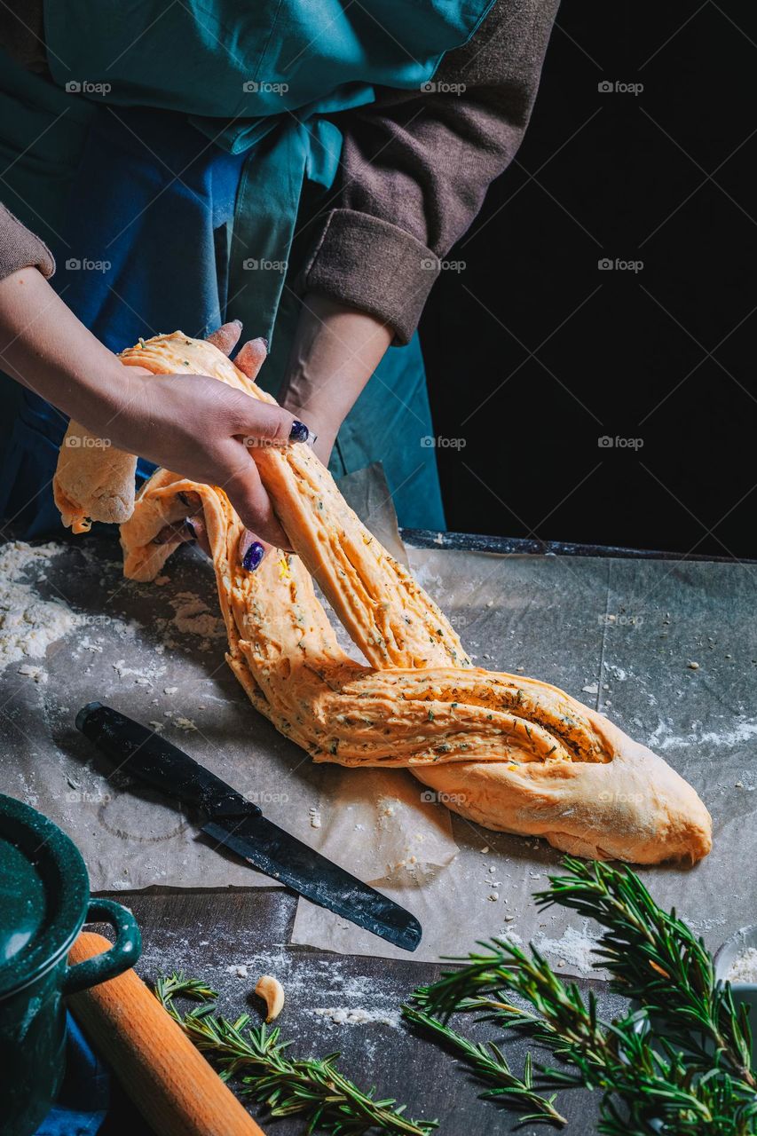 Woman standing in the kitchen by the old wooden table and kneading dough