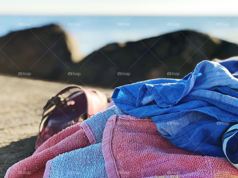 Towel and sandals left on the jetty and the blue sea behind