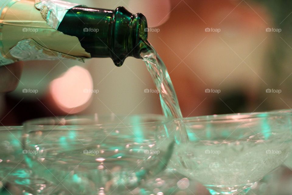 A bottle of champagne being poured into champagne glasses