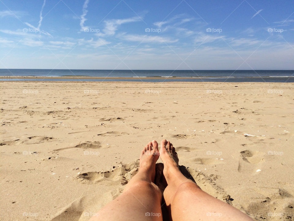 Lying in the sun on the beach looking at my legs. Alone on the beach