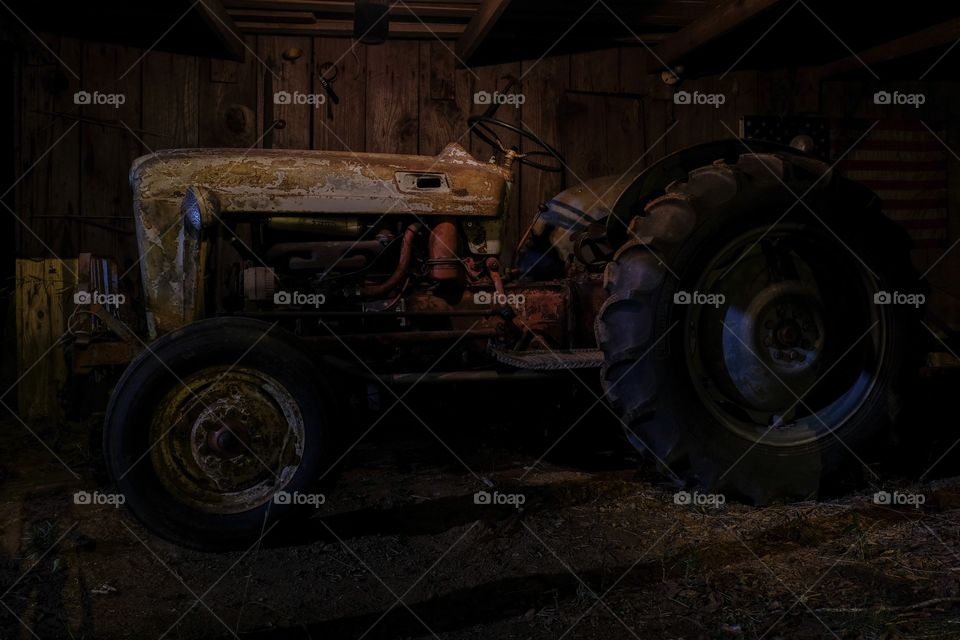 A 1953 Ford Jubilee vintage tractor in a dimly lit barn  that is still operational. 