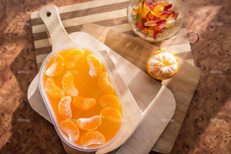 Delicious orange jelly with tangerine slices in a container and jelly worms.