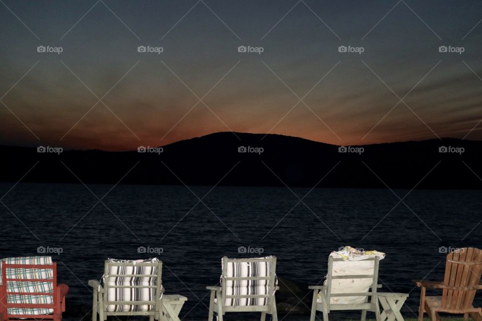 Adirondack and lawn chairs on the shore on mountain lake at sunset in the Adirondack mountains 