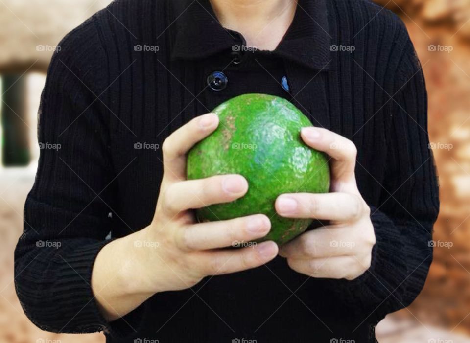 Person holding avocado