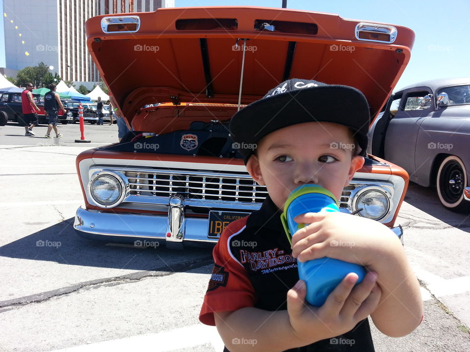 Taking a break. My son taking a sippy break at a classic car show.
