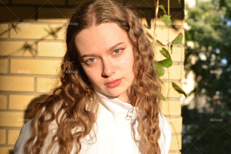 brunette girl beautiful portrait close up in sunlight brick wall background