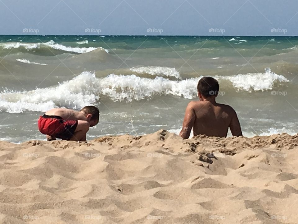 Brother playing in the sand on the beach of Lake Michigan 