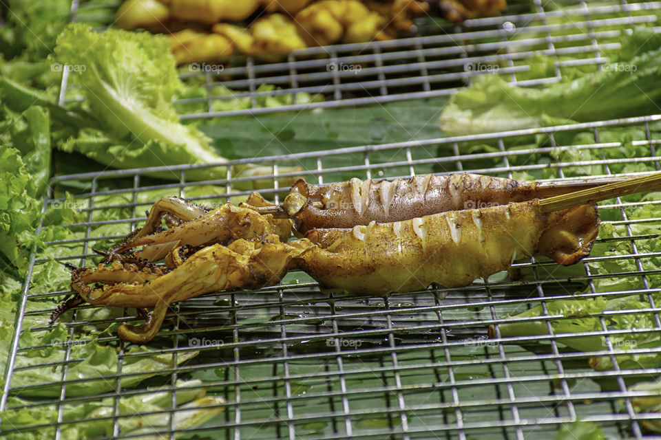 Grilled marinated squid with seafood sauce and vegetables on the steel grilles With the heat.