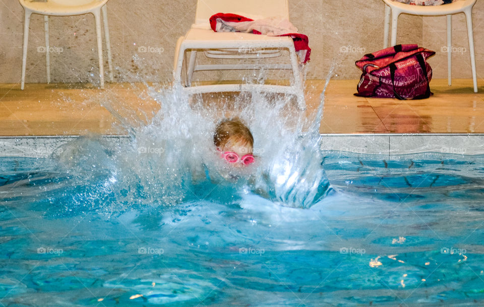 Young girl jumping in the pool.