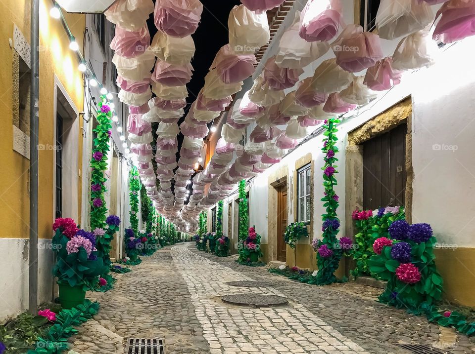 Cobblestone streets decorated with paper flowers for the Festa Dos Tabuleiros in Tomar