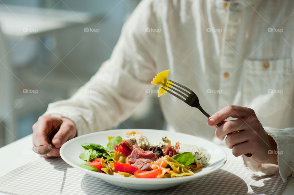 close-up of a young man eating a salad in a light kitchen