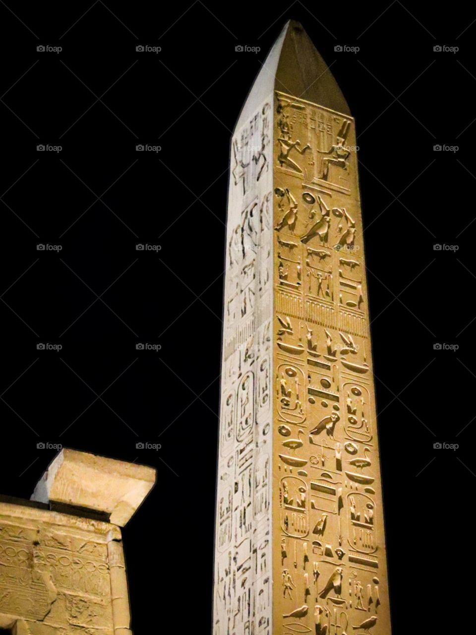 A night picture of an obelisk with hieroglyphic inscriptions, at the Luxor Temple.