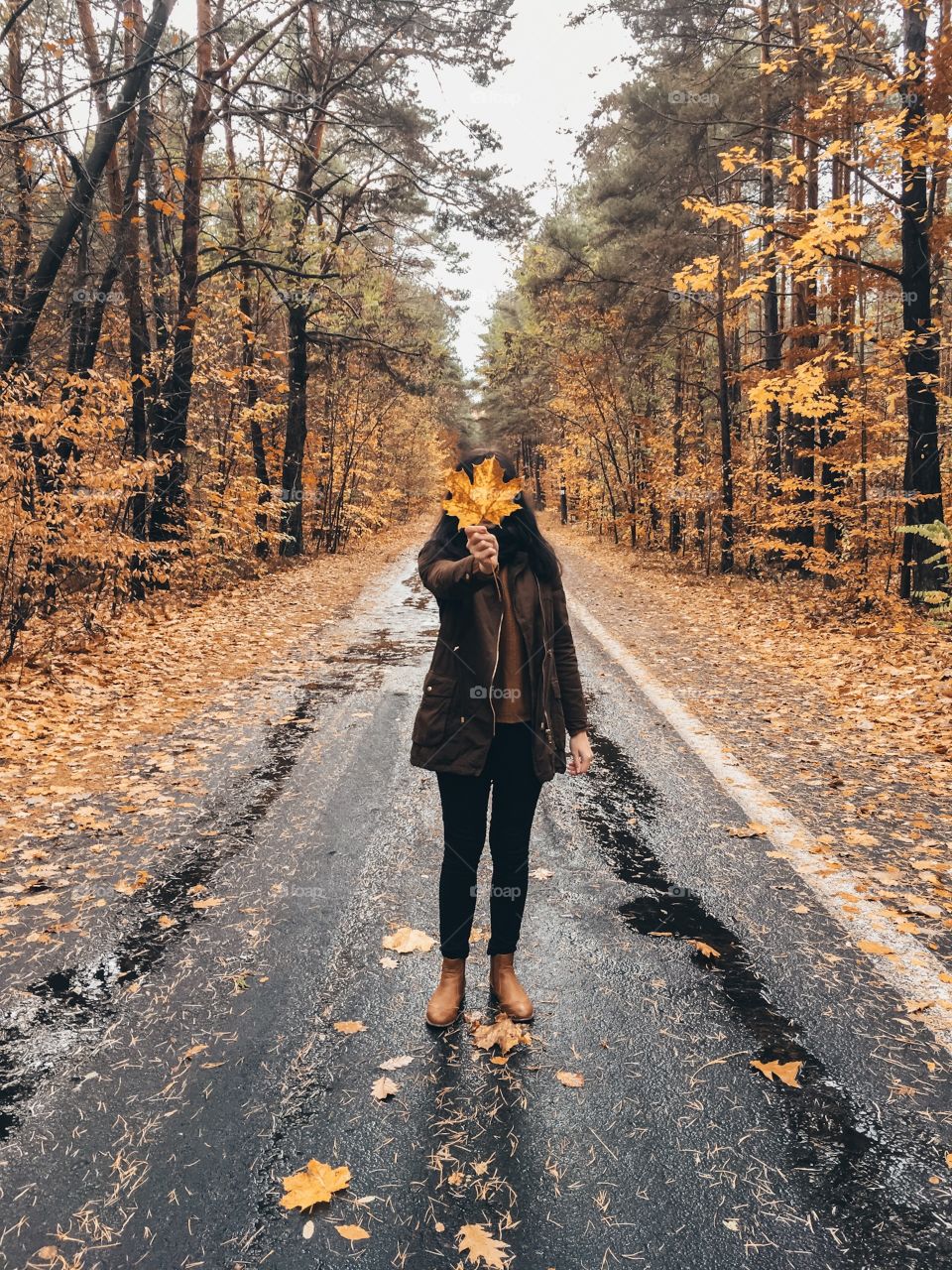 A girl with maple leaf on a forest road. 