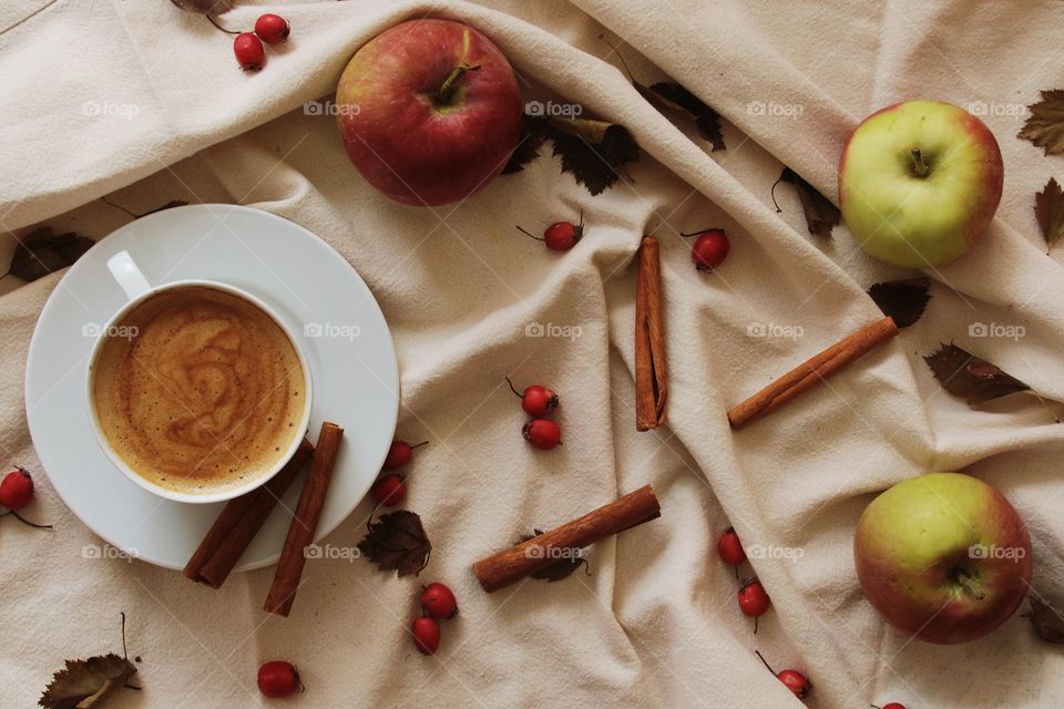 A cup of coffee with cinnamon and apples