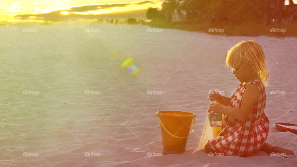 A young girl tries to make a sand castle on a beach during summer
