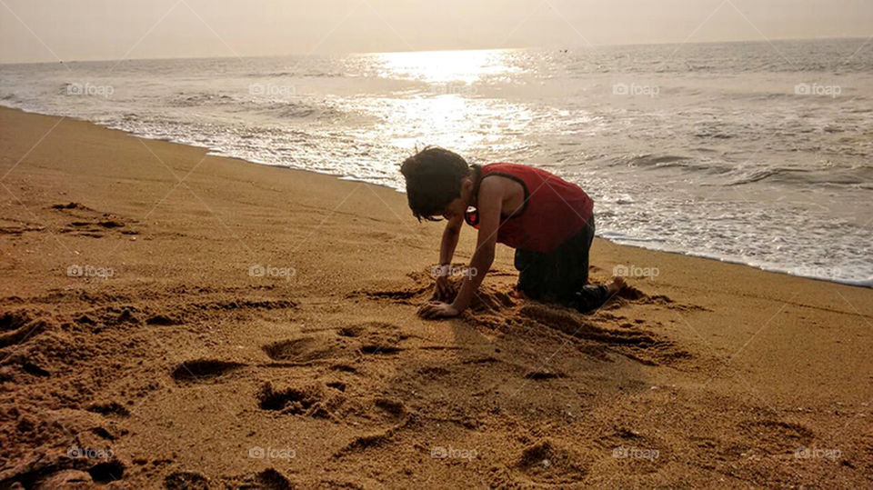 A kid is playing in beach sand