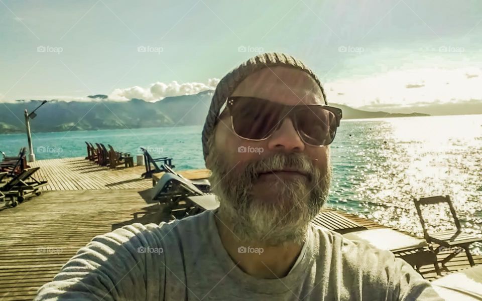 Man taking a selfie in Ilhabela Archipelago. In the background, the Natural Beauties of the Island.