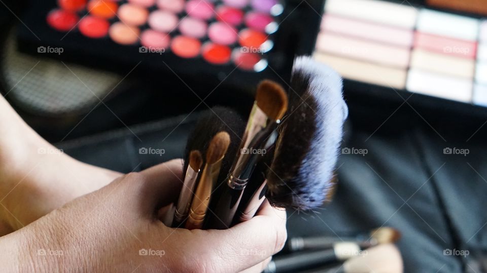 Person's hand holding make-up brushes