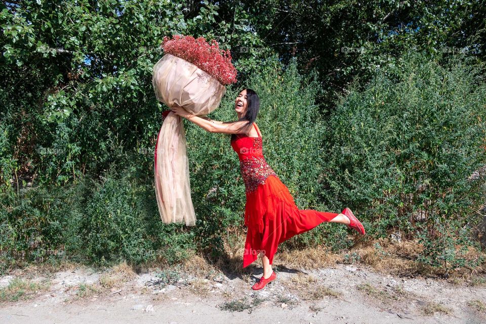 Woman Dances with a Large Bouquet of Red Flowers