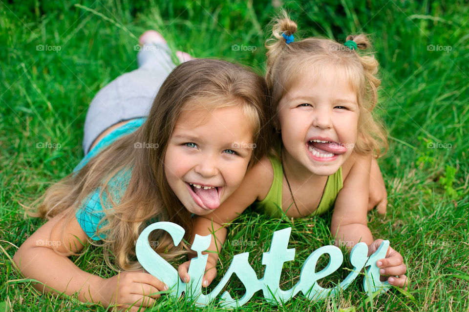 Close-up of two sisters lying on grass