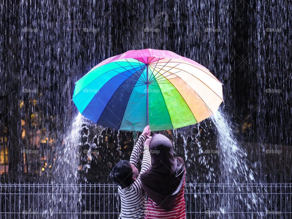 Brother and sister holding the umbrella against the heavy mansoon downpour