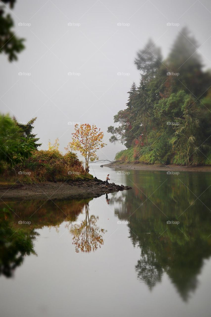 A lone fisherman finds solace in a quiet Washington estuary on a foggy Autumn morning 