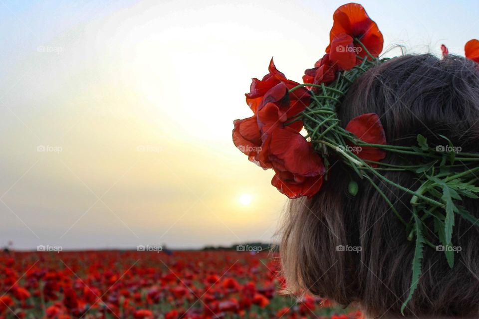 sunset on the poppy field. girl with a wreath