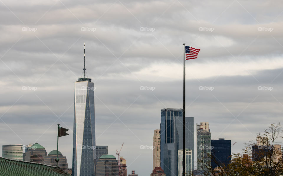 An American flag flying high with One World Trade in the background of New York City.