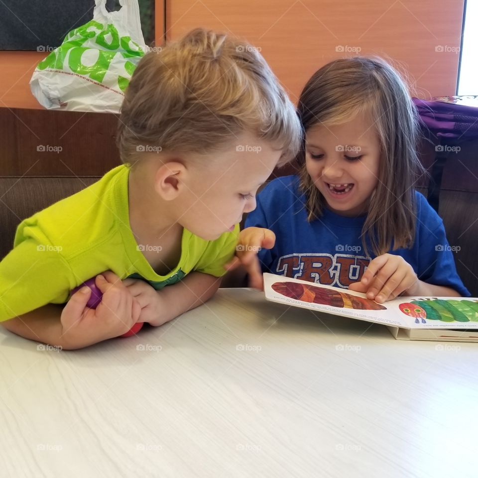 Brother and sister with book at home