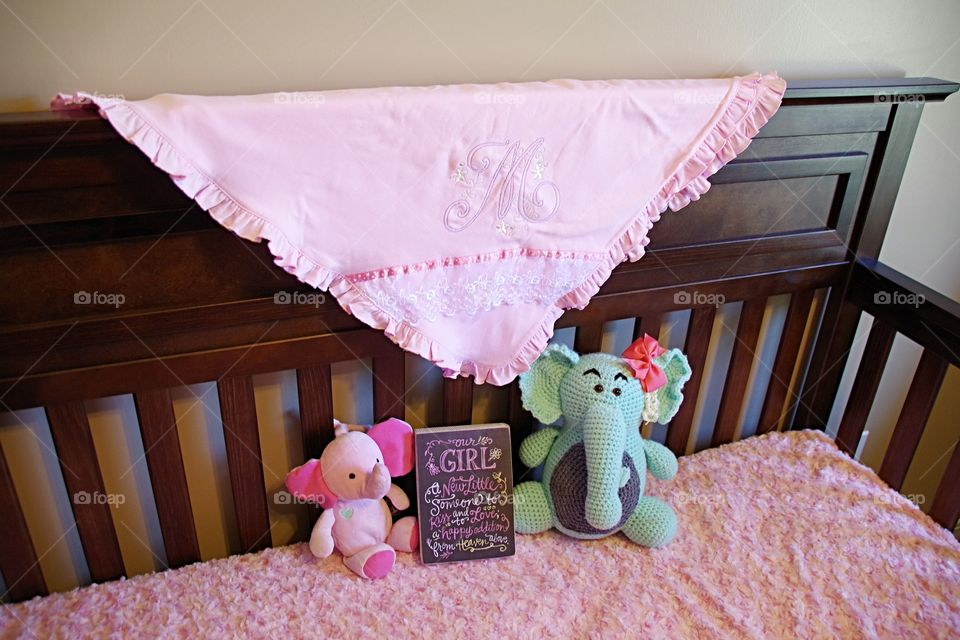 new baby girl crib with pink blanket and toy stuffed elephants