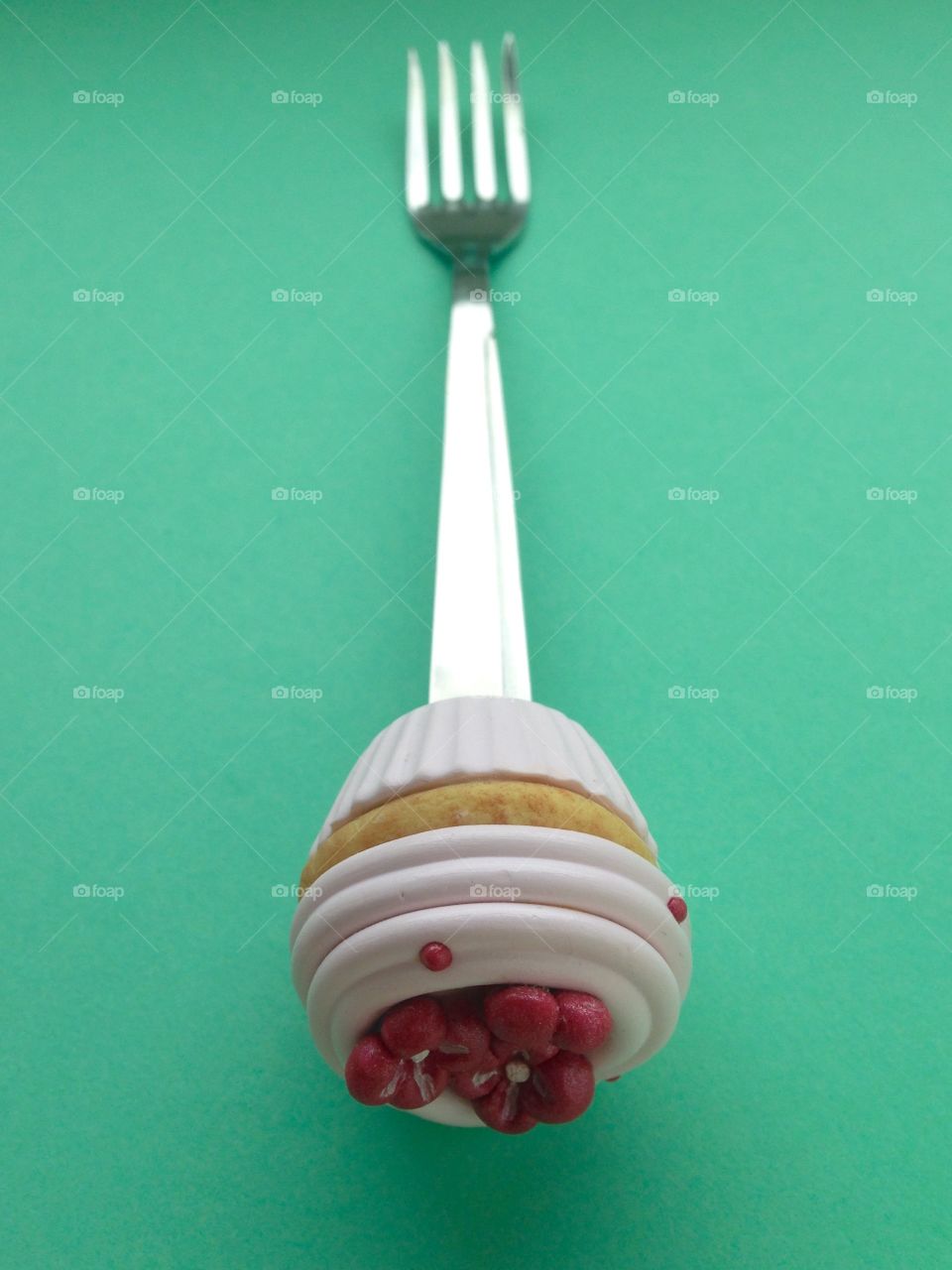 spoon with cupcake on top on green background 