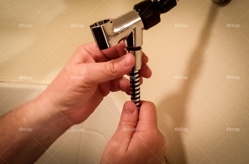 A man's hands installing a shower head