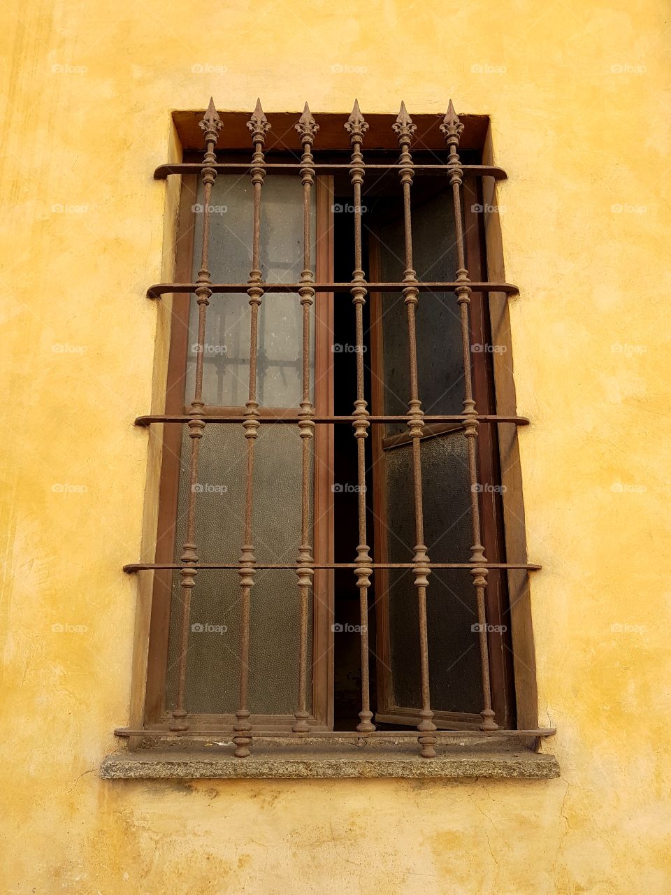 Old window of an abandoned, yellow house