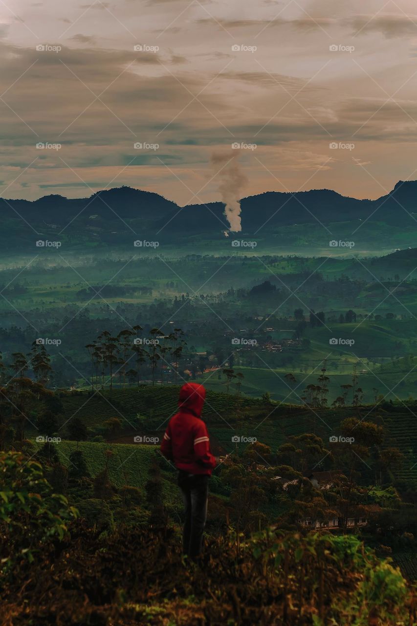 a man enjoying the mountain atmosphere in the morning covered in a light fog