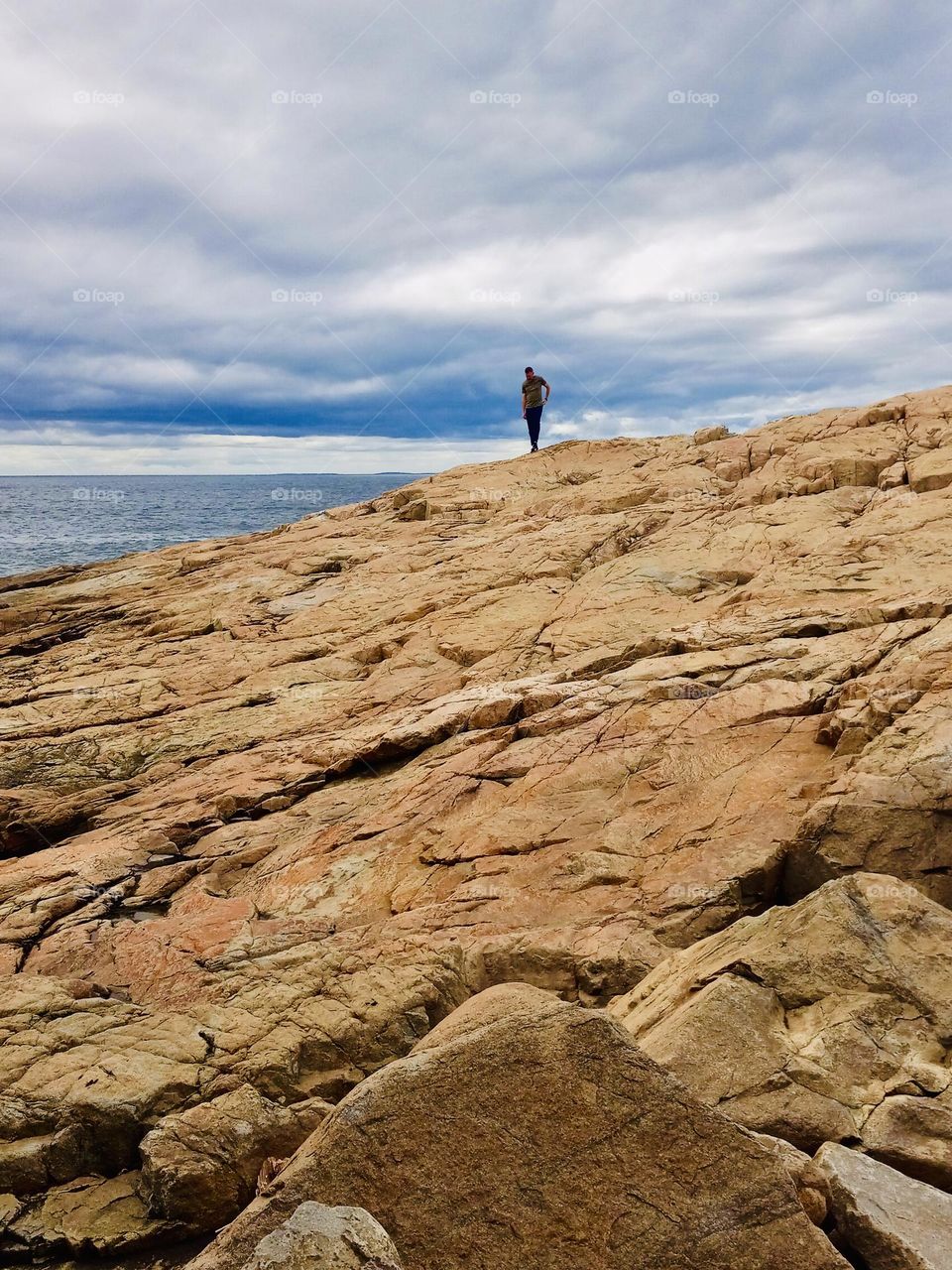 A lone figure admires the ocean from Schoodic Point, Maine.