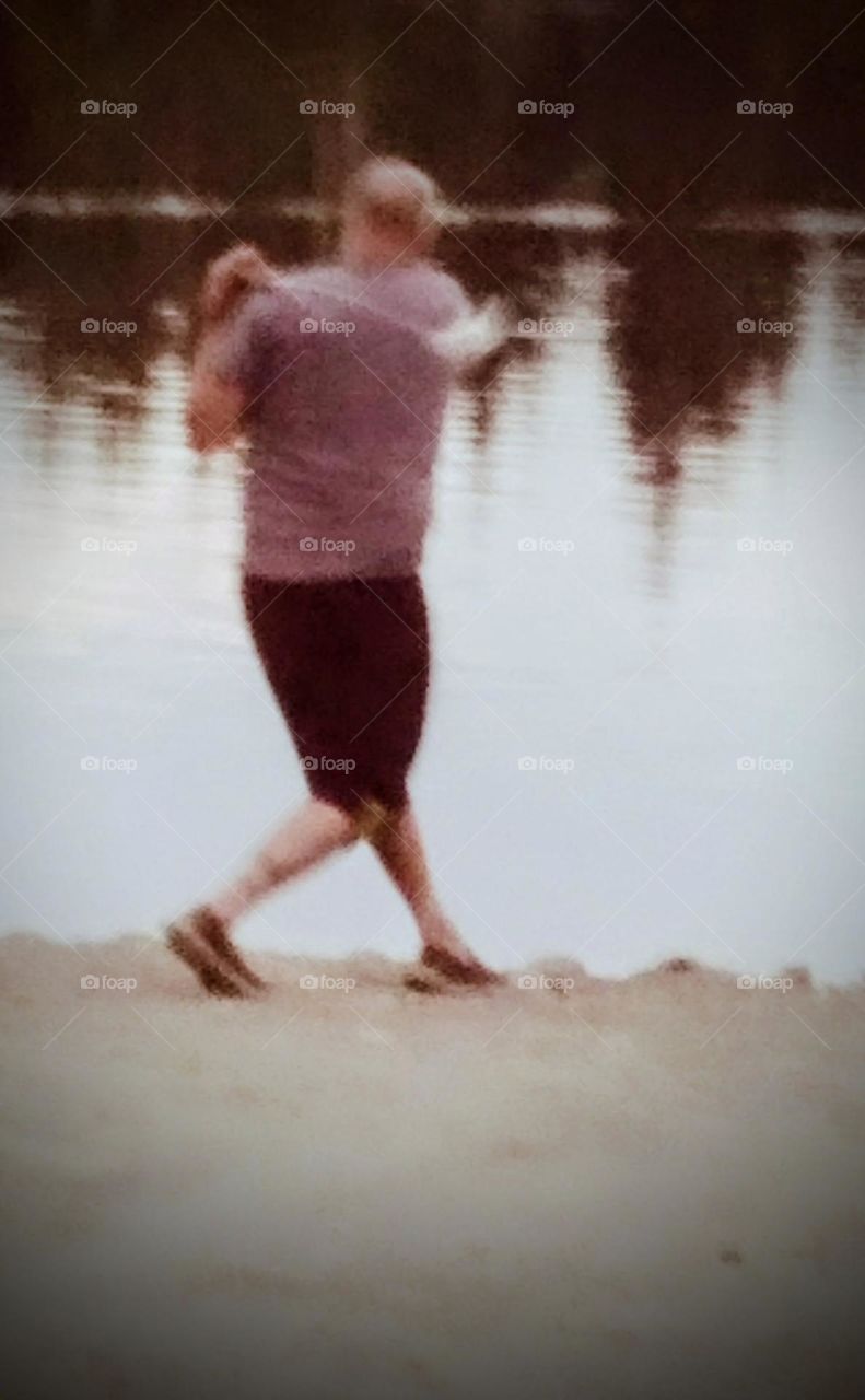 A man at Lake Morton taking advantage of the vast lake front to hit golf balls towards the lake.