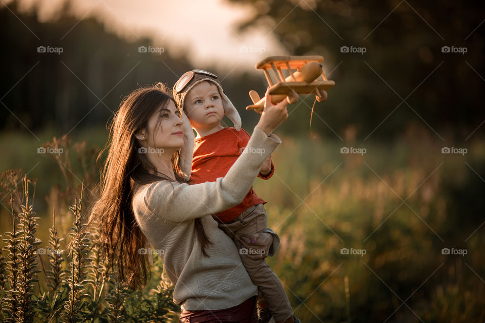 Mother and son with wooden plane at sunset