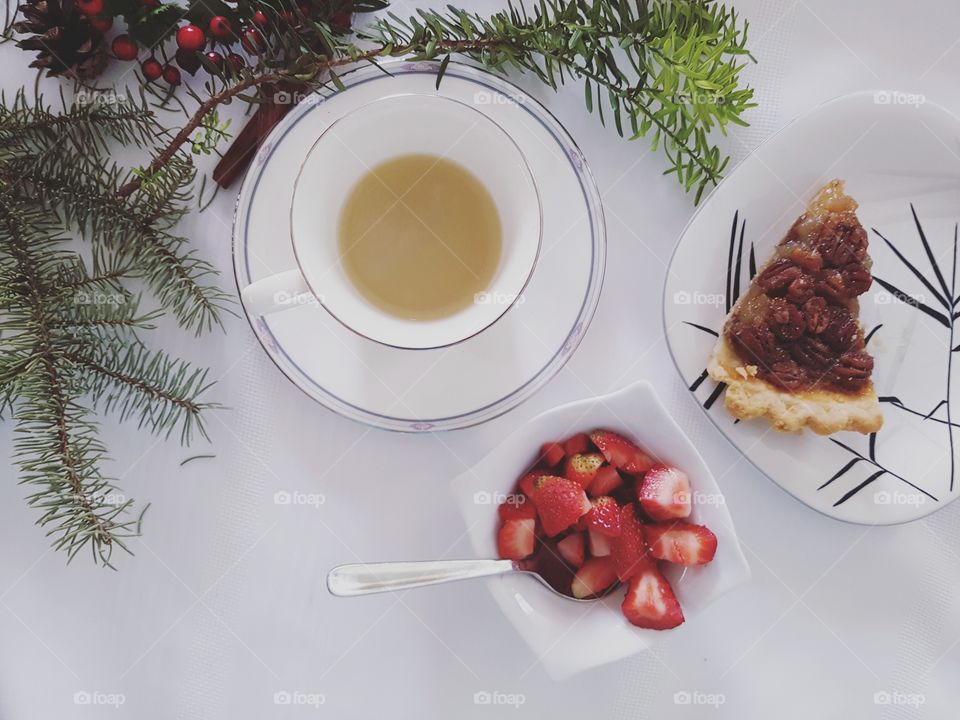 Cup of mint tea, bowl of strawberries and pecan pie on a table