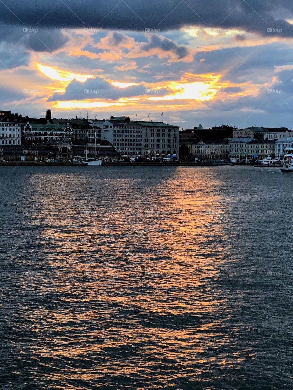 Calm sunset view over the sea bay to the city front facade 