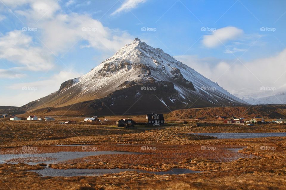 Snow-covered mountain in Iceland with idyllic houses in front of it.