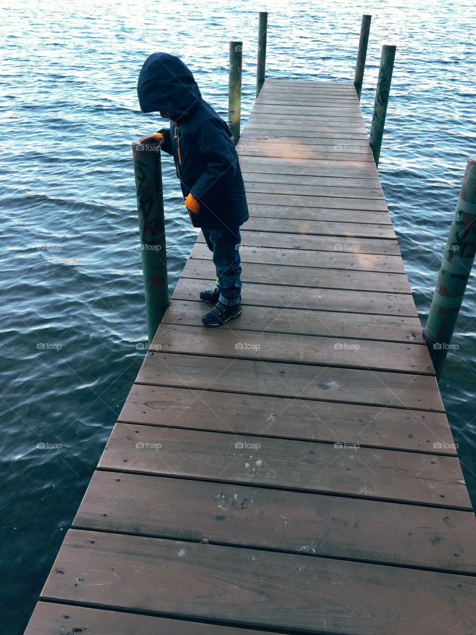 Young boy standing on a jetty. Young boy standing on a jetty in autumn weather